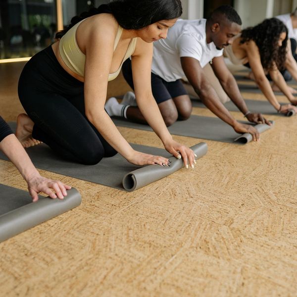Diverse group of people smiling and preparing for a yoga session.